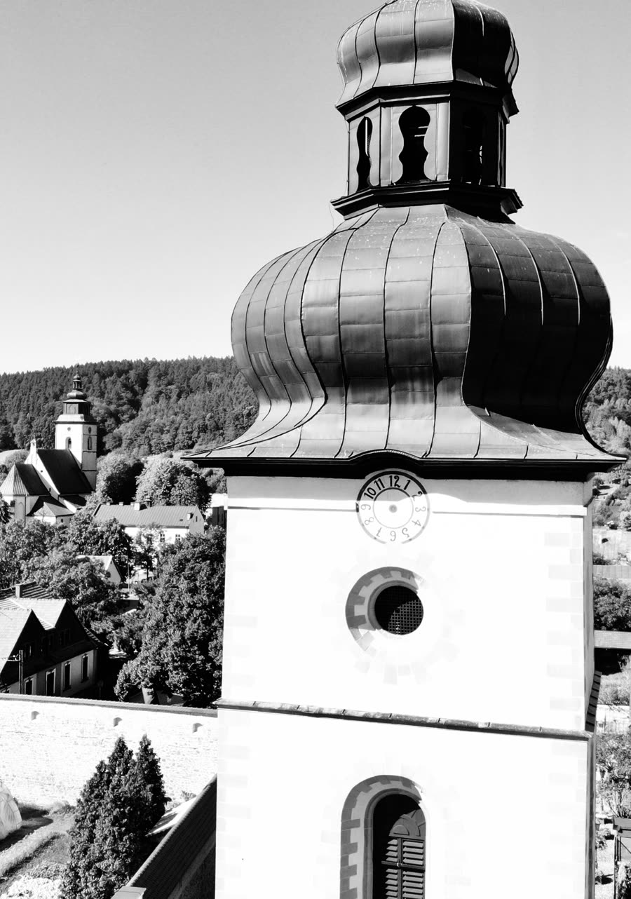 Hełm wieży kościoła klasztornego z zegarem, w tle Stary Sącz; czarno-białe zdjęcie z lotu ptaka